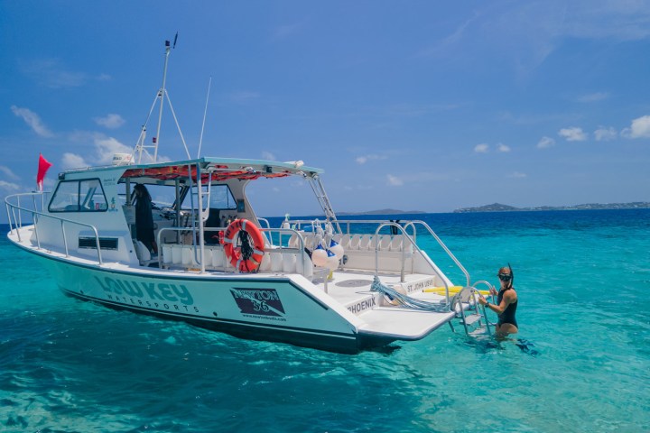 a blue and white boat sitting next to a body of water