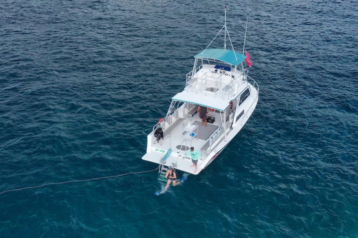 Aerial view of a white boat with a canopy on blue water.